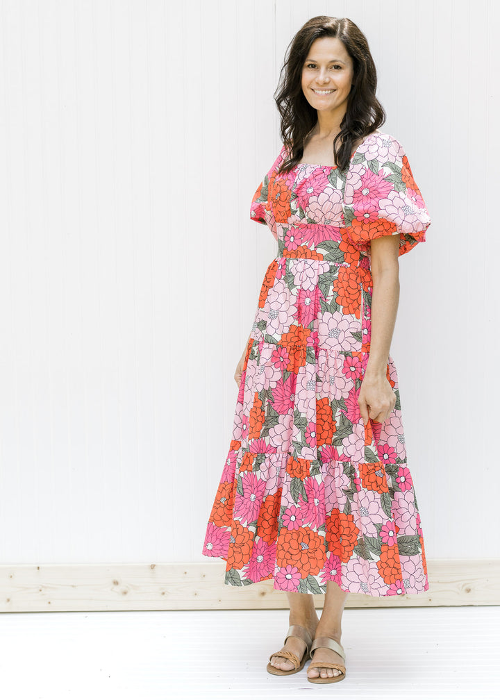 Model wearing a fully lined coral floral midi dress with a square neck and puff short sleeves. 