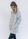 Side view of Model wearing a tweed sweater with a turtleneck, long sleeves and pockets. 