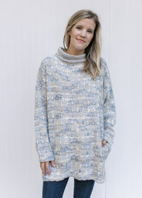 Model wearing jeans with a tweed sweater with a turtleneck, long sleeves and pockets. 