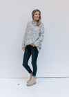 Model wearing jeans and booties with a tweed sweater with a turtleneck, long sleeves and pockets. 