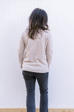 Back view of Model wearing a taupe sweater with gold sequin stars, long sleeves.