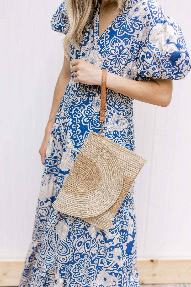 Model holding a natural straw purse with a two tone design, with wrist band.