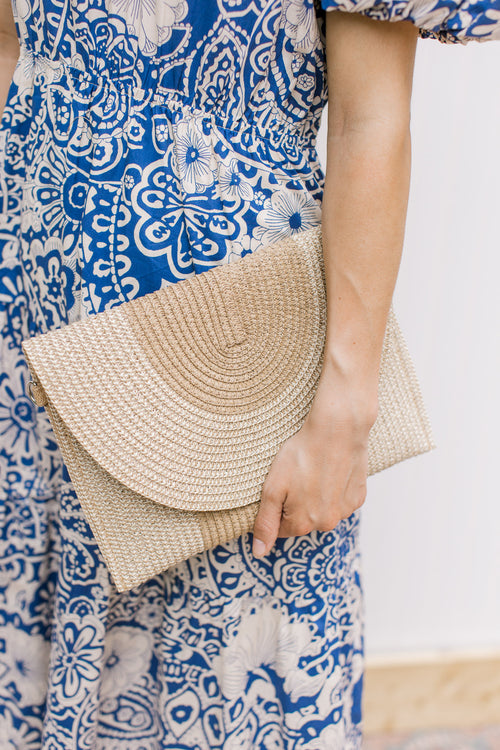 Model holding a straw purse with a two tone design, that transitions from clutch to crossbody