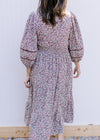 Back view of Model wearing a cream dress with plum ditsy flowers, 3/4 sleeve and a smocked waist.