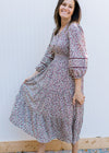 Model wearing a cream dress with plum ditsy flowers, 3/4 sleeve, smocked waist and v-neck. 