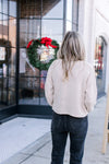 Back view of Model wearing a creamy knit cardigan with long sleeves and a slightly  cropped fit.