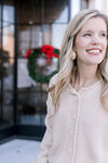 Close up of knit material and button front on a cream colored cardigan with long sleeves. 