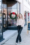 Model wearing jeans and a creamy knit cardigan with long sleeves and a slightly  cropped fit.