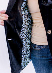 Model showing the lining on a fully lined black velvet jacket with long sleeves and faux pockets. 