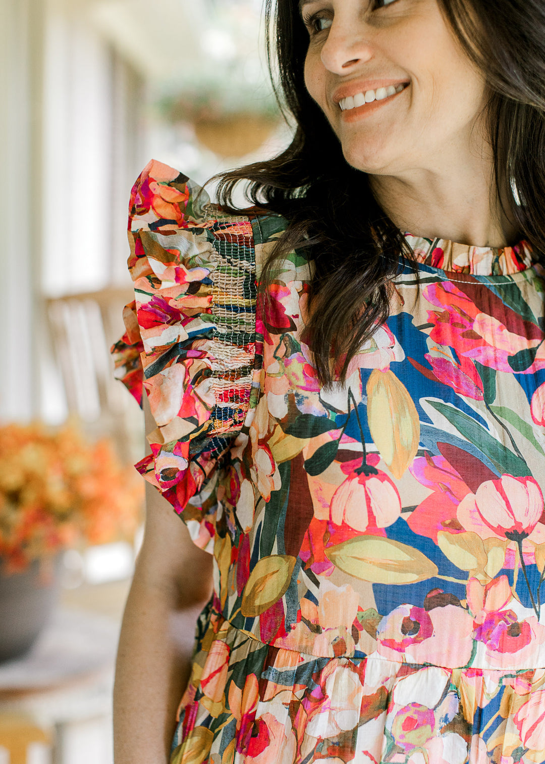 Close up of flutter cap sleeves and round neck with ruffle on a bright floral midi and tiered skirt.