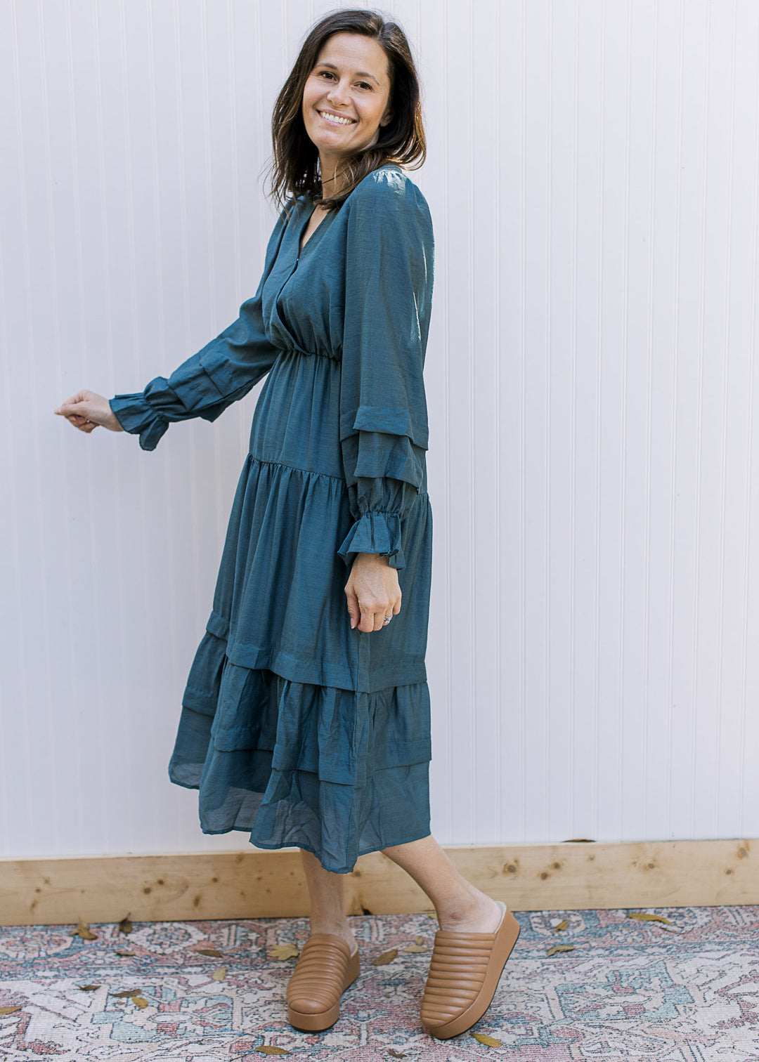 Model wearing mules with a dusty blue midi with poet sleeves, elastic at bust and tiered skirt. 