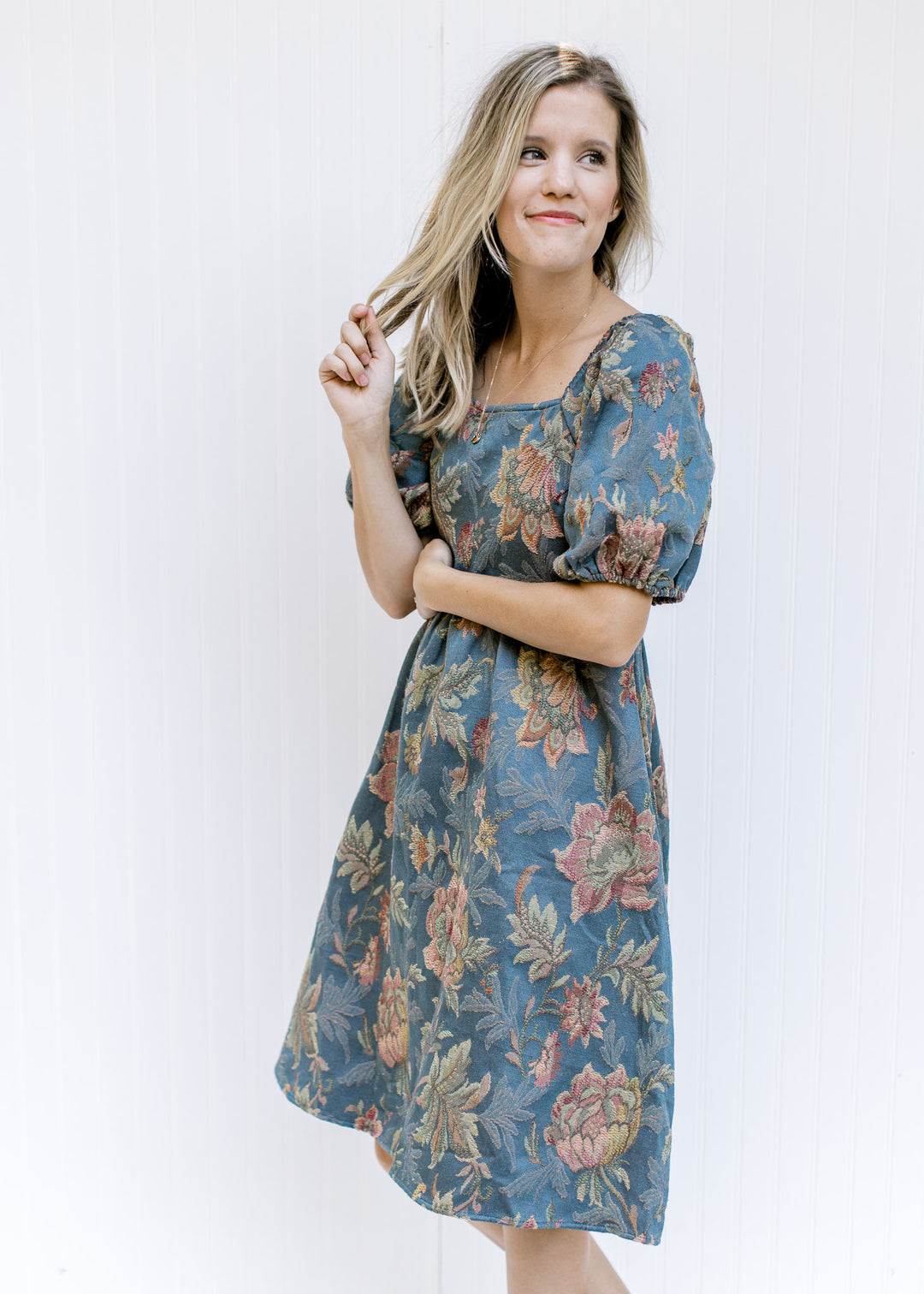 Model wearing a blue midi dress with floral stitching, a square neckline and bubble short sleeves. 