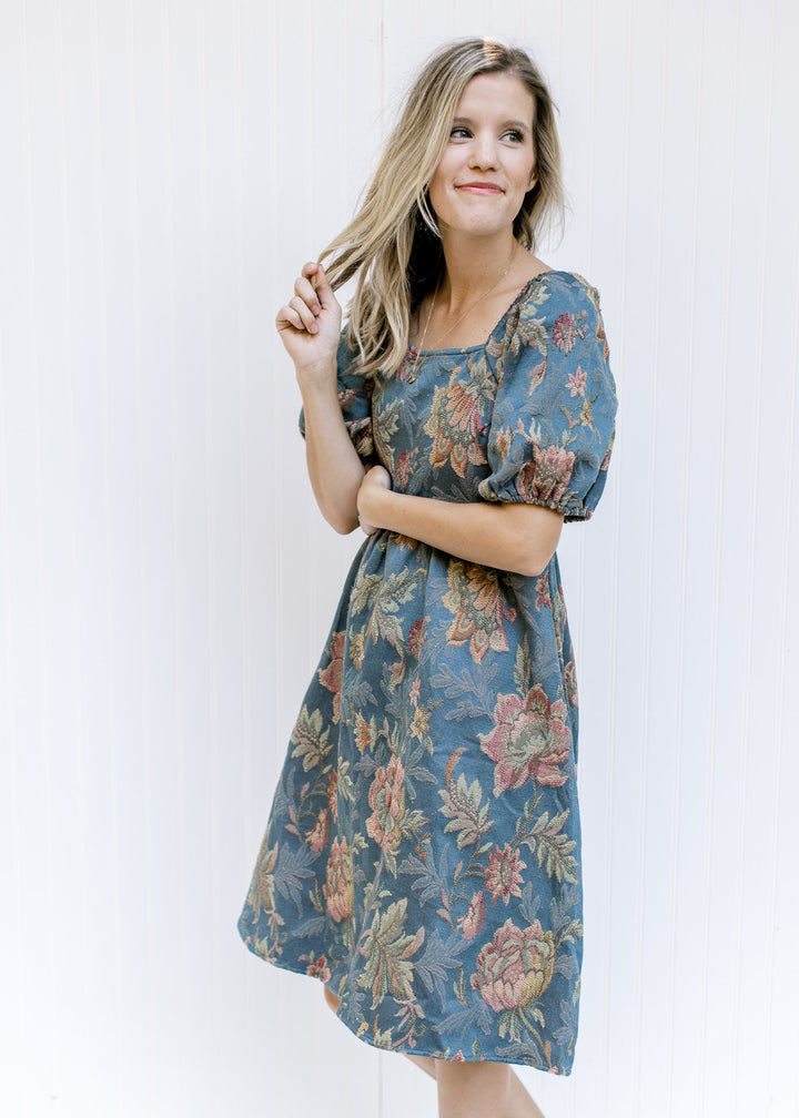 Model wearing a blue midi dress with floral stitching, a square neckline and bubble short sleeves. 