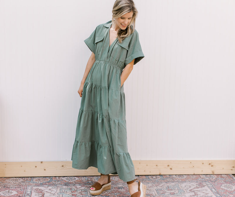 Model wearing a tiered green maxi with patch pockets, v-neck and short sleeves.