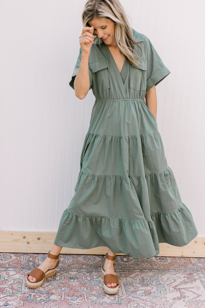 Model wearing a cotton green dress with elastic waist, patch pockets and short sleeves.