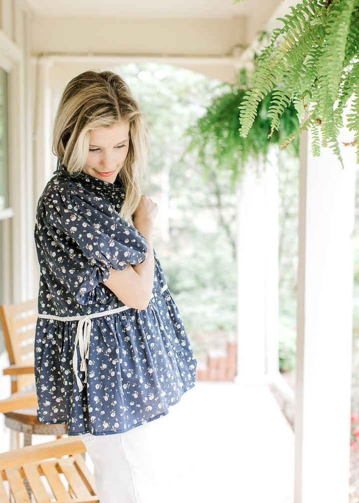 View of side tie detail and short puff sleeves on a navy top with white ditsy flowers. 