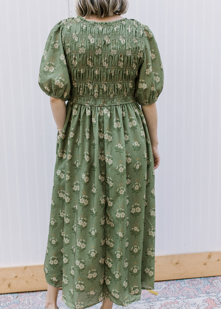 Back view of Model wearing an olive midi with cream floral, smocked bodice and elbow sleeves. 