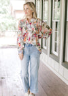 Model wearing a floral long sleeve top with a pleated bodice, covered buttons and wide cuffs. 