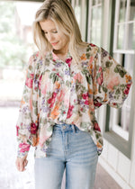 Model wearing jeans and a floral long sleeve top with a pleated bodice, and wide cuffs. 