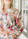Close up of pleated bodice and covered buttons on a floral long sleeve top. 