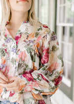 Close up of pleated bodice and covered buttons on a floral long sleeve top. 