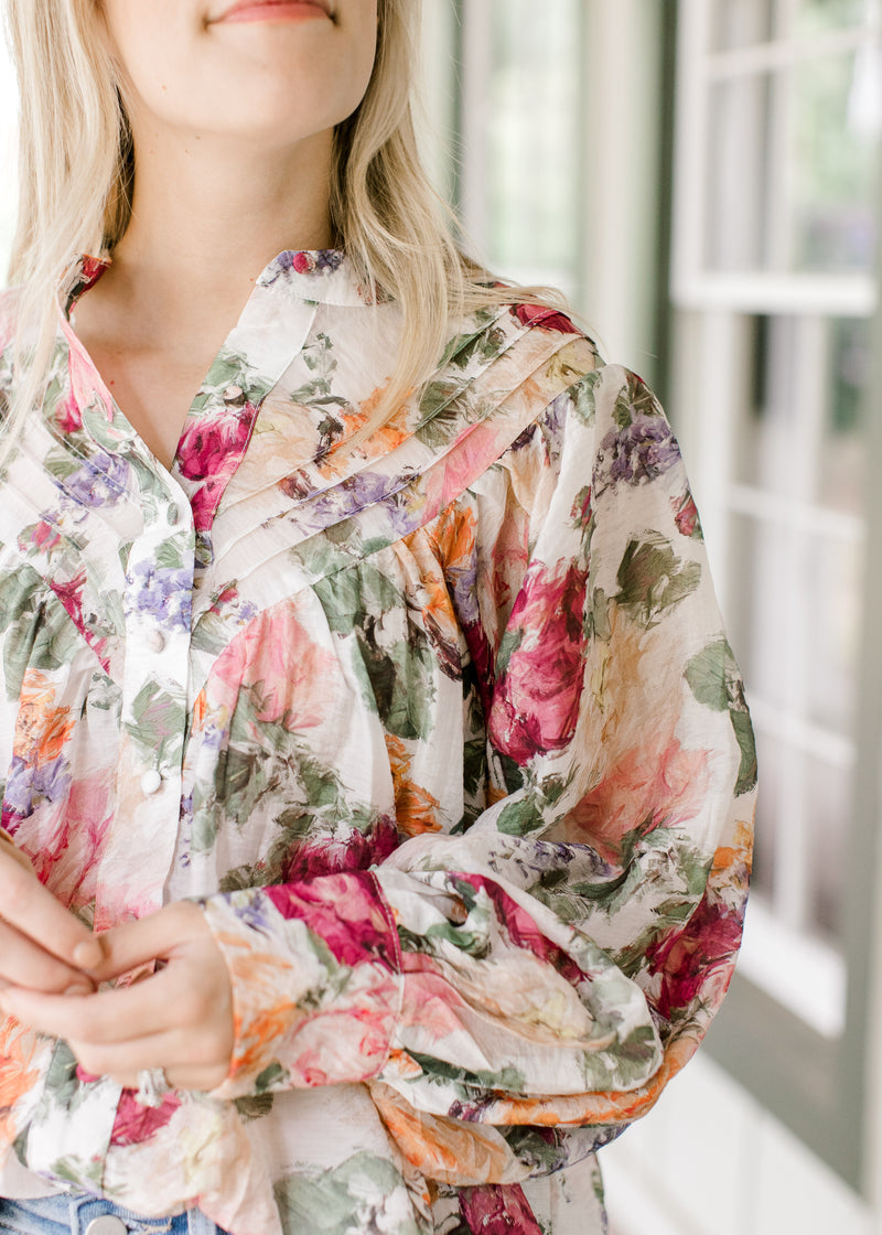 Close up of pleated bodice and covered buttons on a floral long sleeve top. 