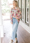 Model wearing jeans, mules and a floral long sleeve top with a pleated bodice and covered buttons. 