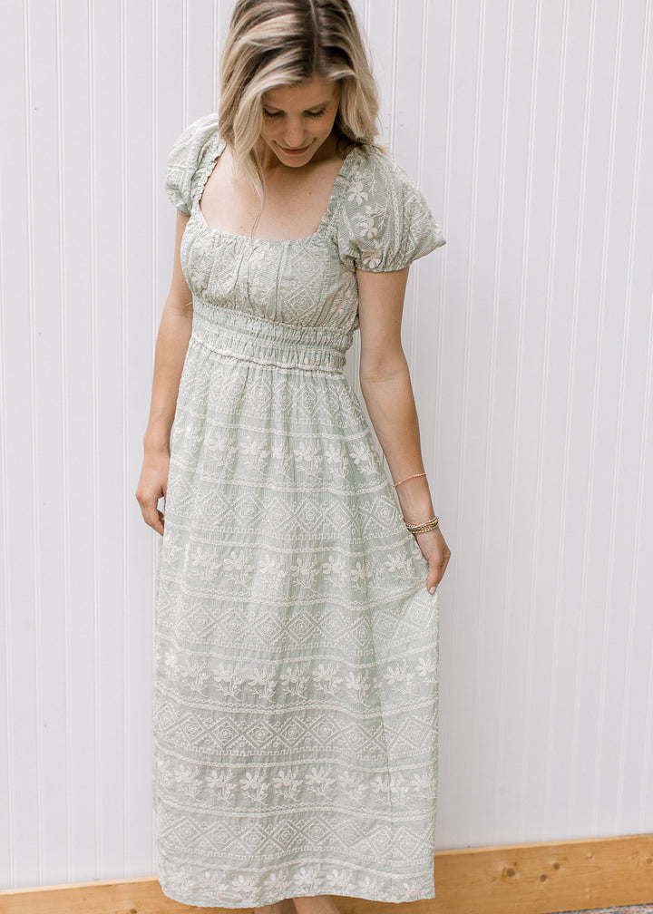 Model wearing a sage maxi with cream embroidered floral, smocked waist and puff cap sleeves.