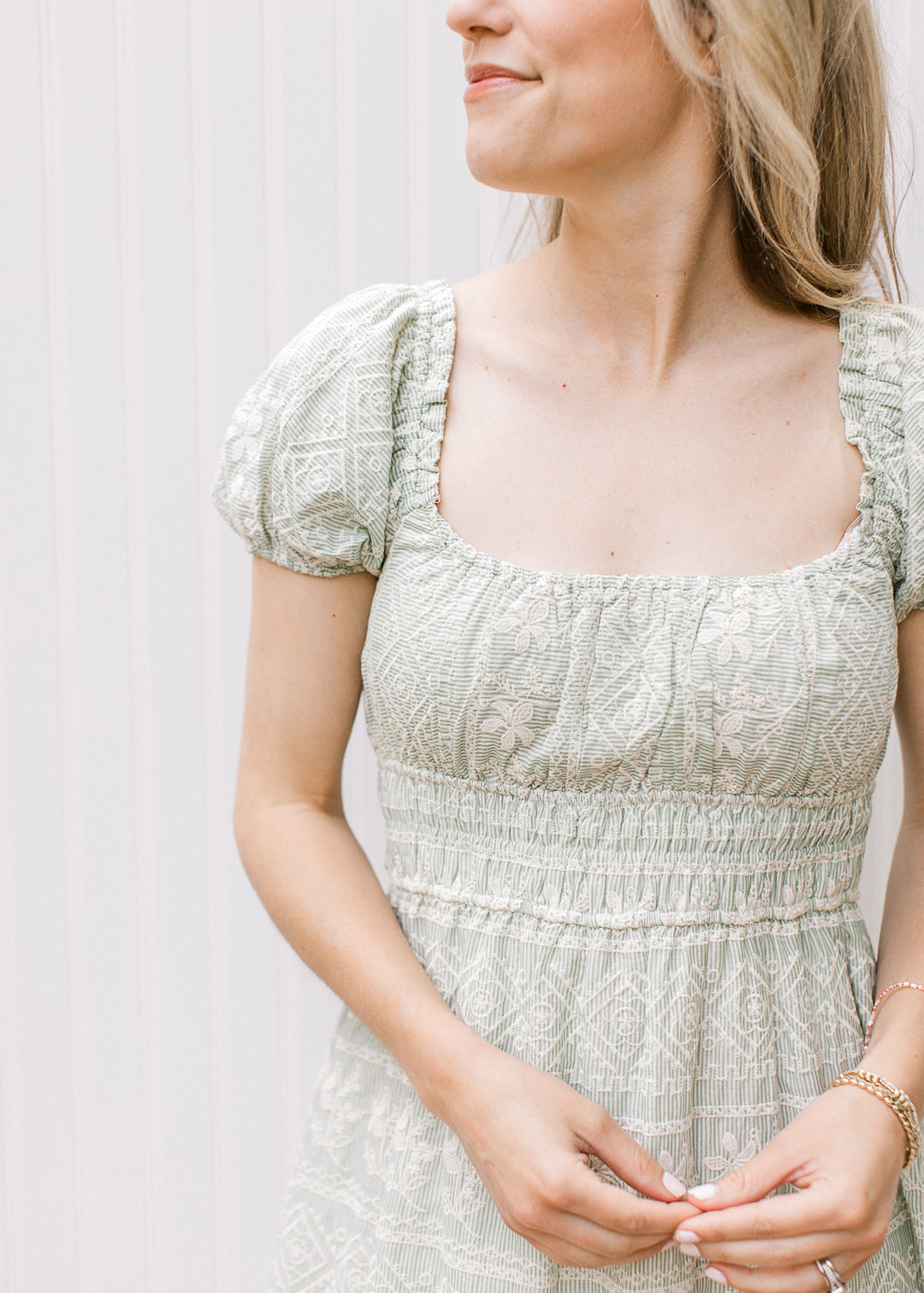 Close up of square neck and short puff sleeves on a sage maxi with cream embroidered floral. 