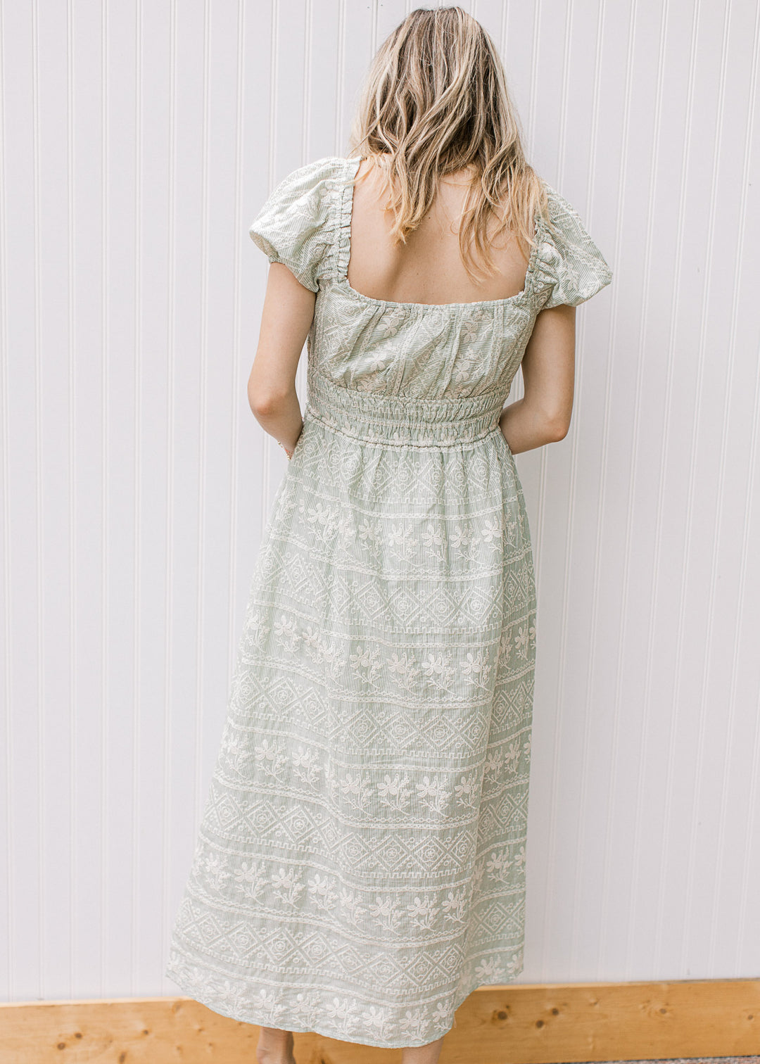 Back view of Model wearing a sage maxi with cream floral, square neck and smocked waist. 