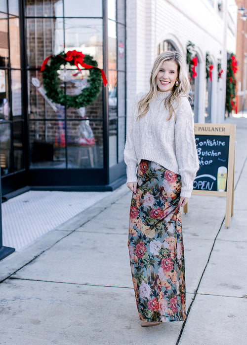 Model wearing a slim fit maxi with a silky deep sage fabric with warm floral and a hidden back zip.
