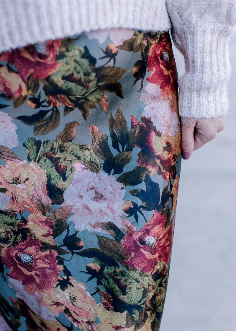 Close up on warm floral on a sage background of a maxi skirt with a back zipper and silky material. 