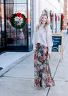 Model wearing a cream sweater, booties and  a silky sage maxi with warm floral.