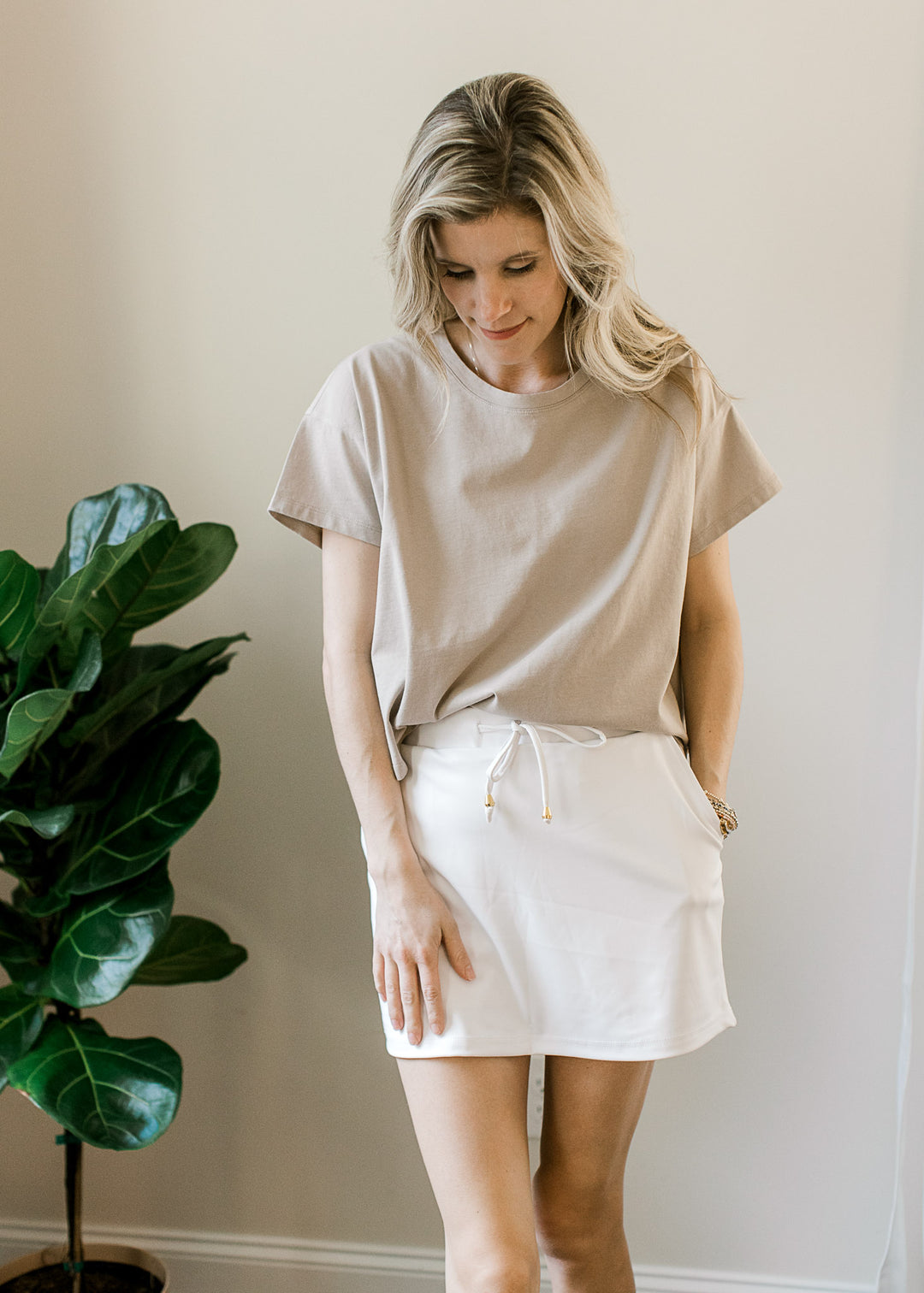 Model wearing a white skirt with a slightly cropped tan top with short sleeves and a round neckline.