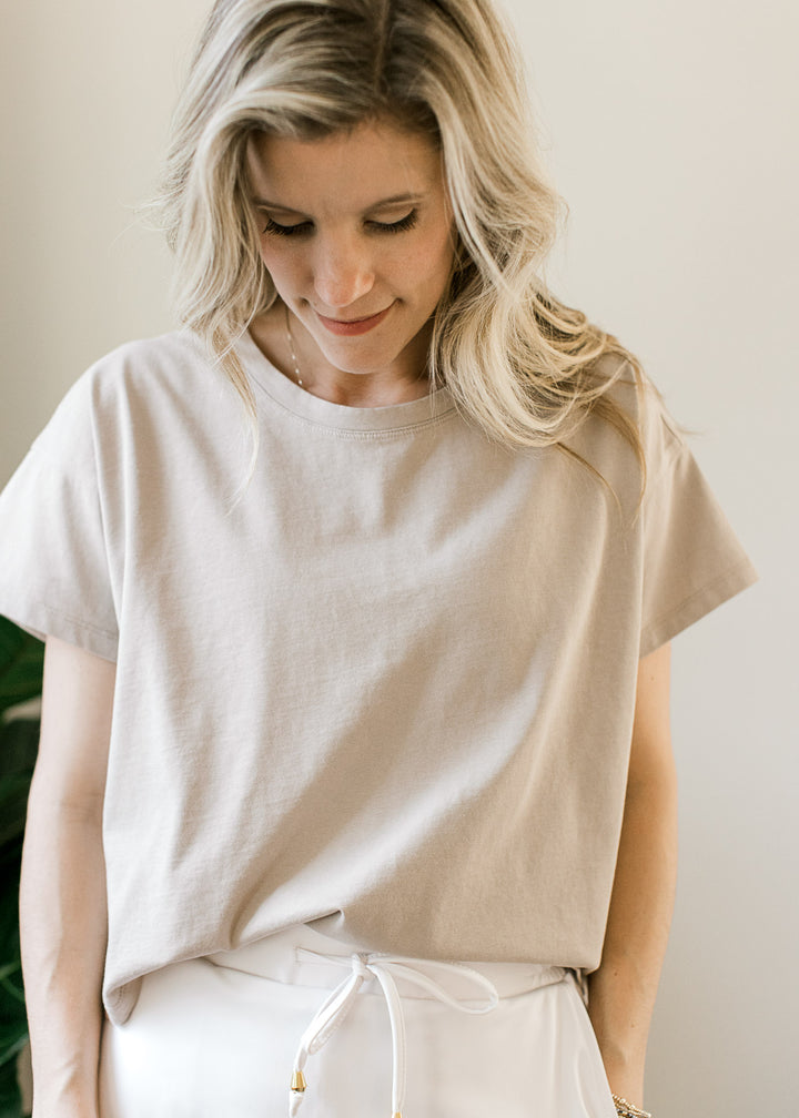 Model wearing a tan top with a slightly cropped fit, short sleeves and a round neck. 