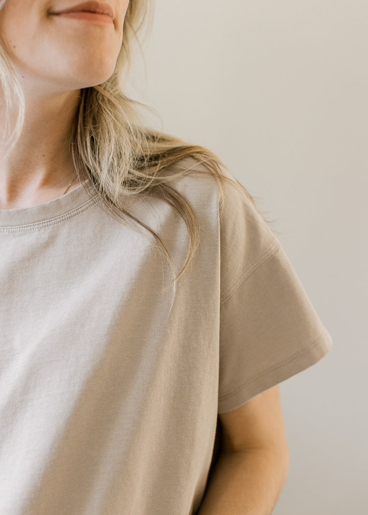 Close up of short sleeve and round neck on a tan top with a slightly cropped fit. 