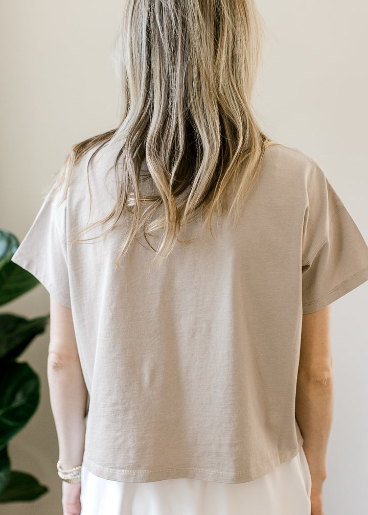 Back view of Model wearing a white top with a slightly cropped fit, short sleeves and a round neck.