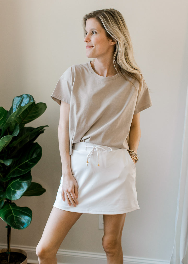 Model wearing a tan top with a slightly cropped fit, short sleeves and a round neckline.