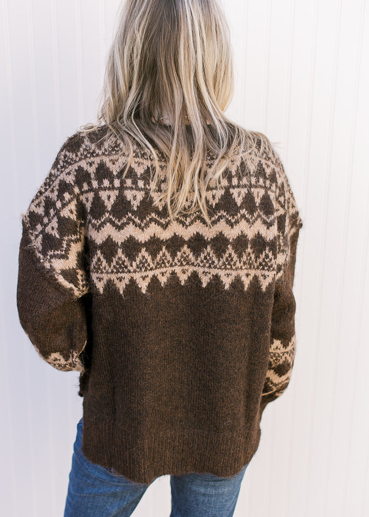 Back view of Model wearing a brown sweater with tan geometric pattern, round neck and long sleeves. 