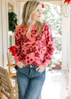 Model wearing a rose colored sweater with burgundy floral, ribbed material and long sleeves. 