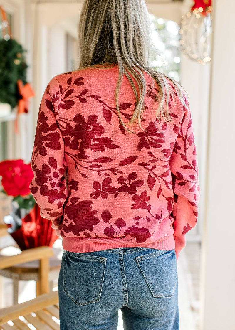 Back view of Model wearing a rose sweater with burgundy floral and long sleeves. 