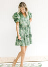 Model wearing an above the knee tiered dress with a green and cream pattern and layered short sleeve