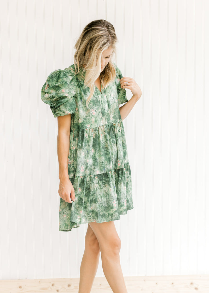 Model wearing an above the knee, tiered dress with green and white design and layered sleeves.