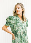 Close up view of v-neck and layered short sleeves on a green and cream dress. 