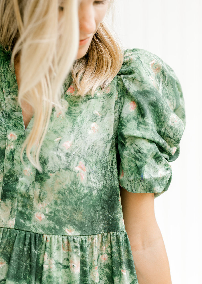 Close up view of layered short sleeve on a model wearing an above the knee green and cream dress.