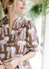 Close up of mauve scalloped details at sleeve and neck of a brown top with cream and mauve bows.