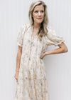 Model wearing a cream dress with watercolor flowers, short sleeves with elastic and a tie v-neck.