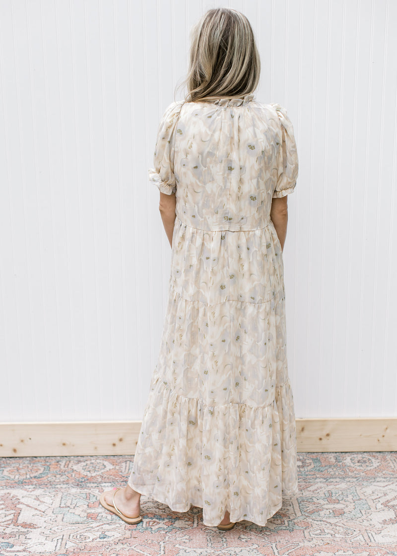 Back view of Model wearing a cream dress with watercolor flowers, short sleeves and a tie v-neck.