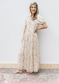 Model wearing sandals with a cream dress with watercolor flowers, short sleeves  and a tie v-neck.