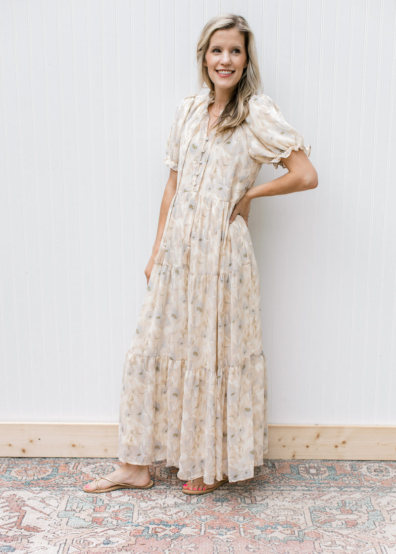 Model wearing sandals with a cream dress with watercolor flowers, short sleeves  and a tie v-neck.
